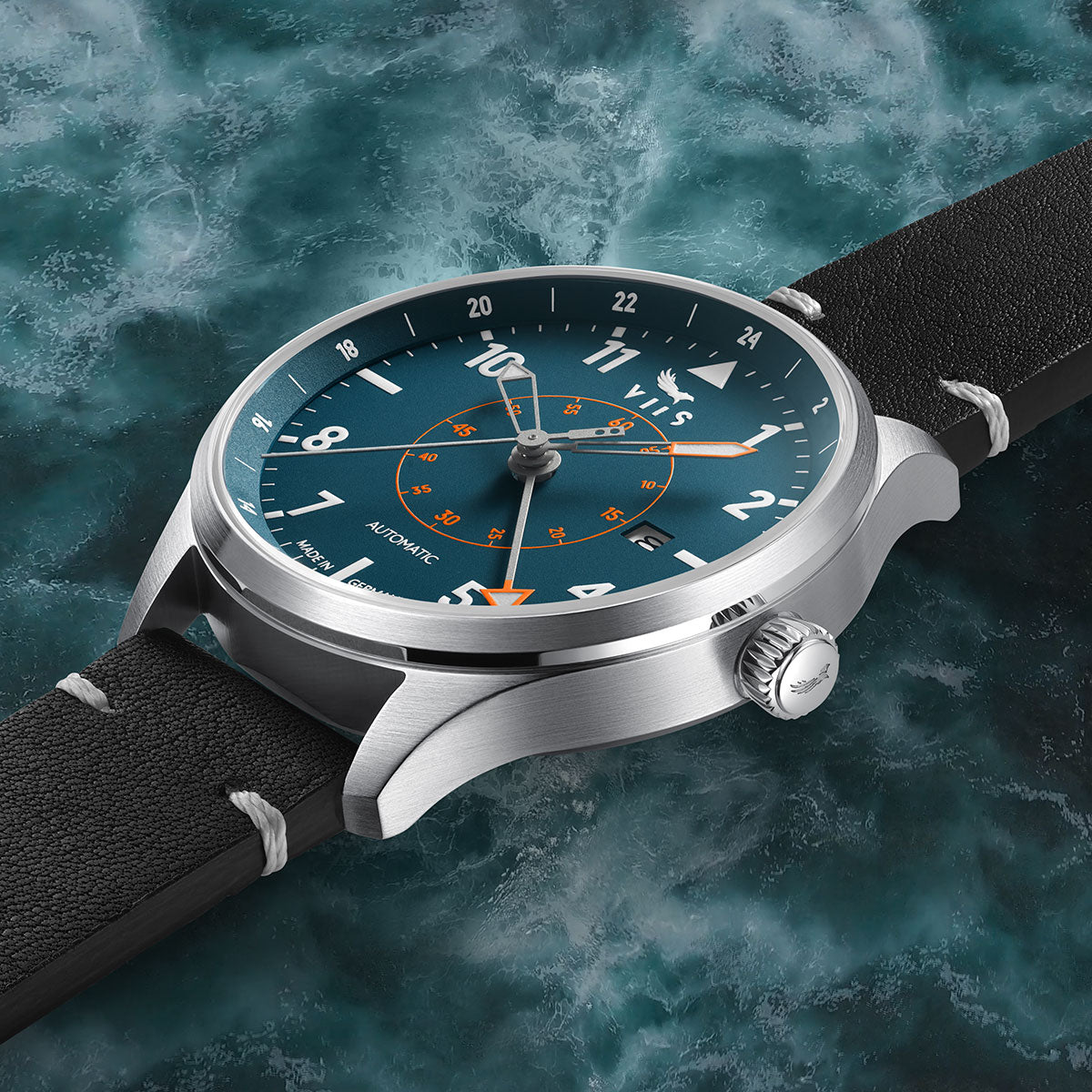 Seitenansicht der VIIS Flieger GMT 42 „Adriatic“ – blaue Fliegeruhr mit Edelstahlgehäuse vor meerblauem Hintergrund, wodurch die verwendeten, hochwertigen Materialien zum Ausdruck kommen.